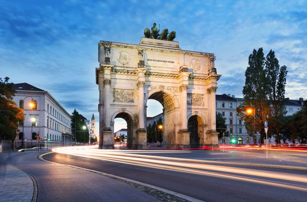 Geheimtipps zum Wohnen in München: Siegestor im Westend bei Abenddämmerung mit beleuchteten Straßen und Verkehrsspuren