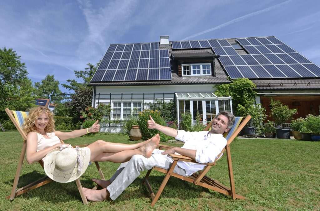 Paar entspannt im Garten vor einem Haus mit Solarpanelen – Symbol für Energieeffizienz und Immobilienpreise in München 2025